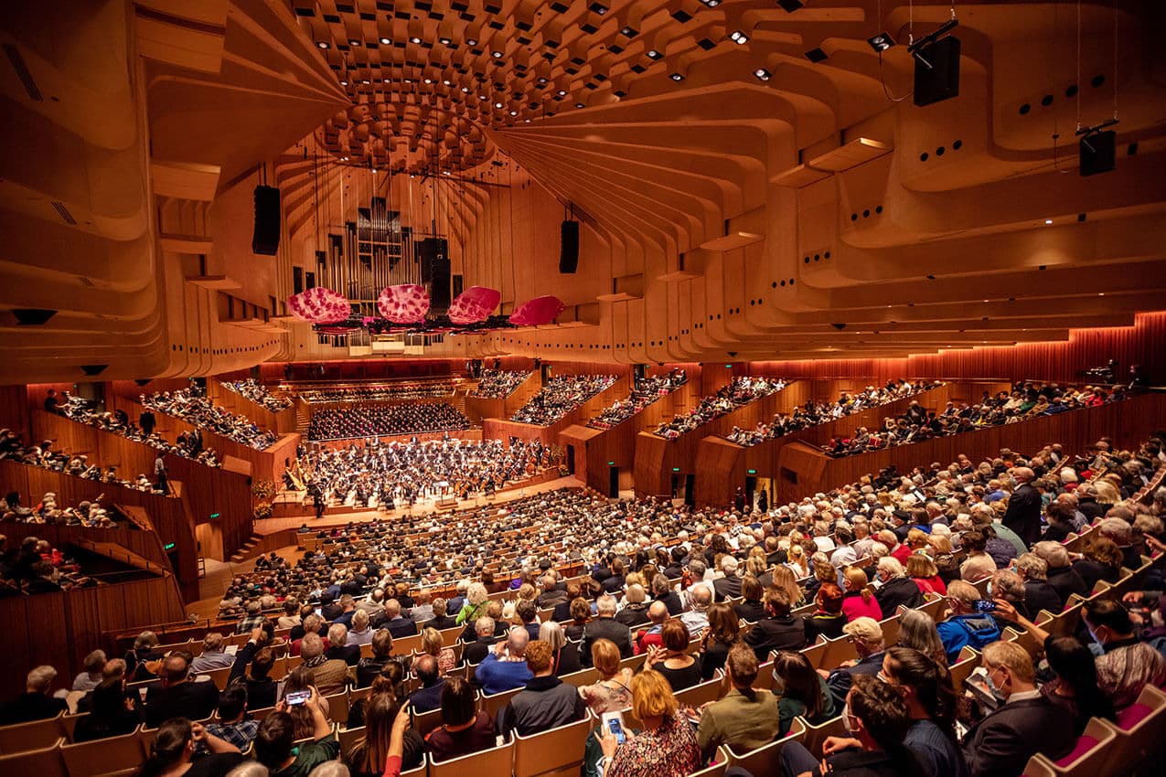 A full concert hall gathered around a symphony orchestra