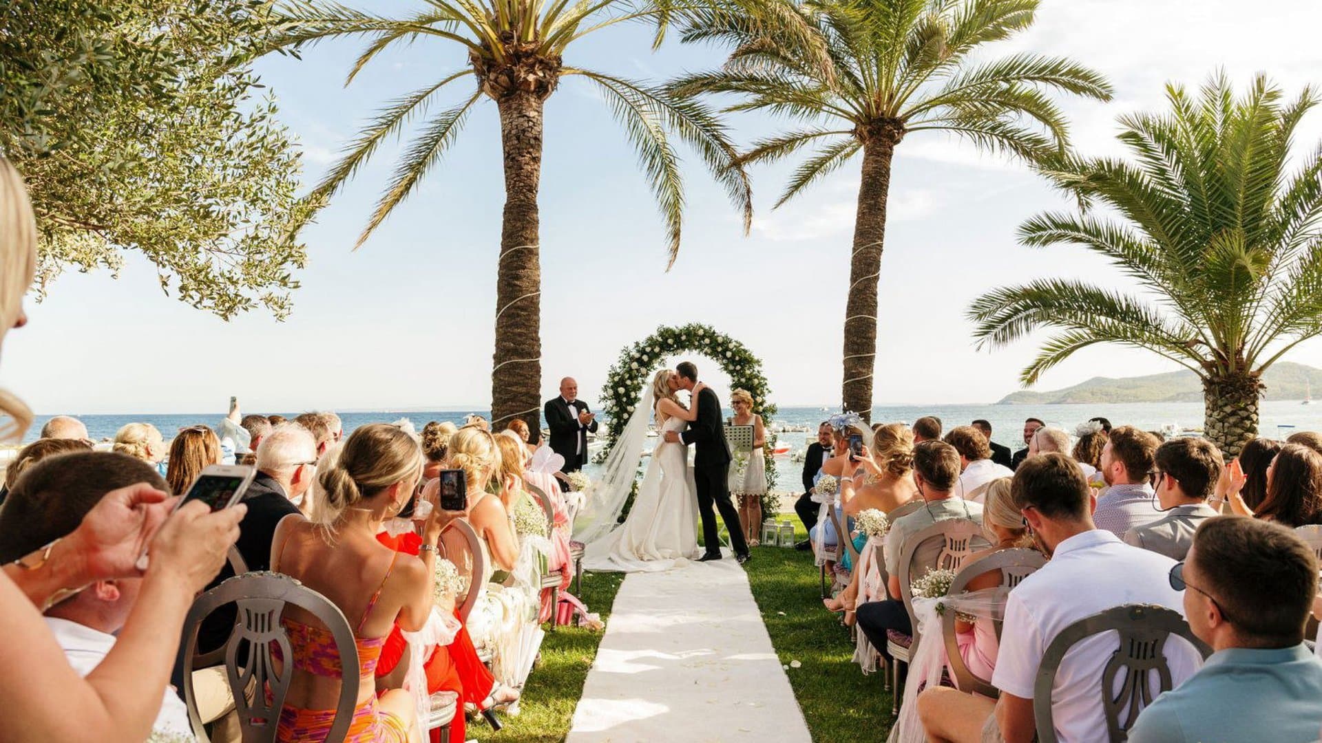 A couple exchanging vows at a palm-lined seaside wedding